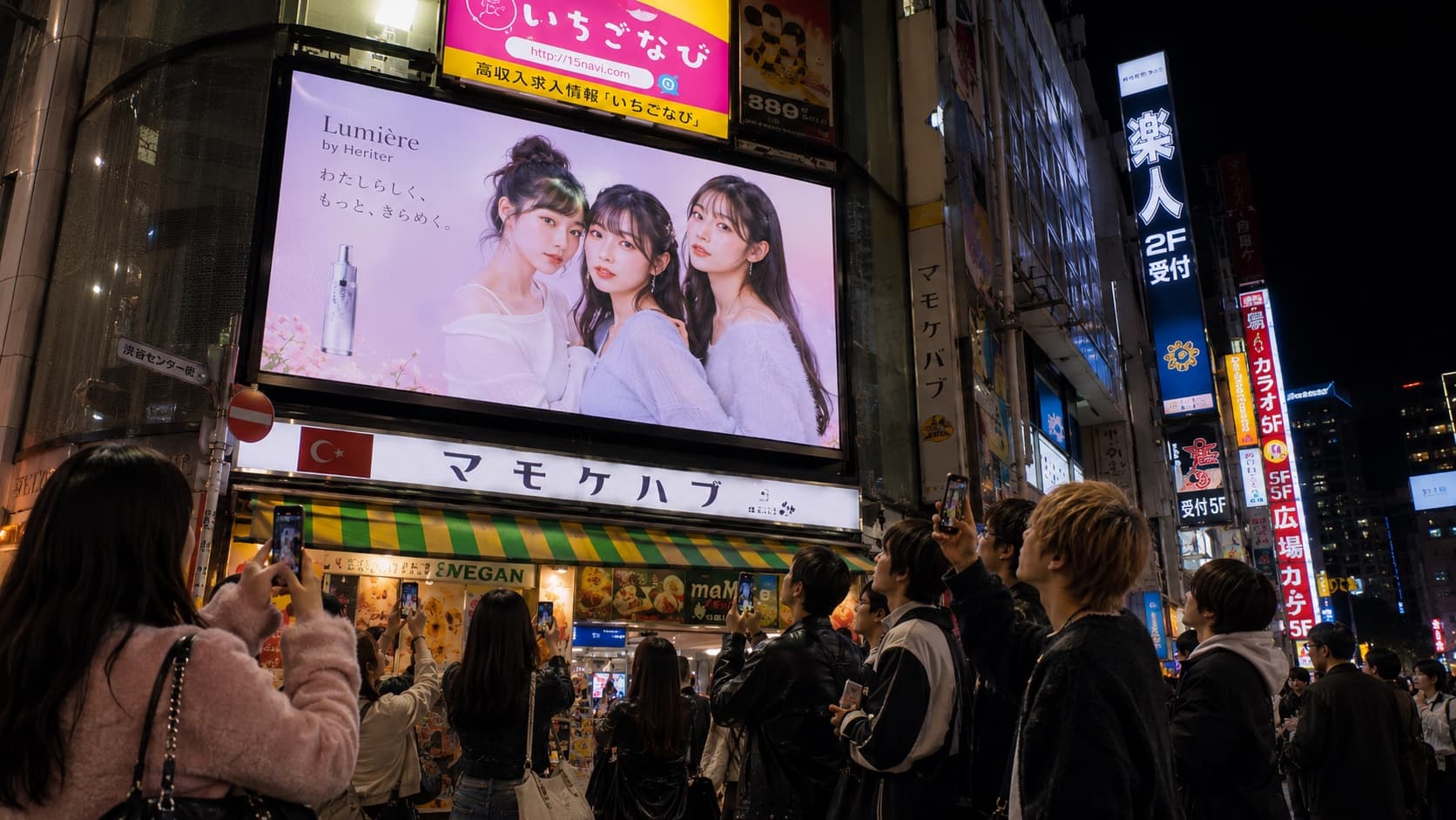 渋谷センター街のミチビト サイネージに通行人がスマートフォンを向けている様子