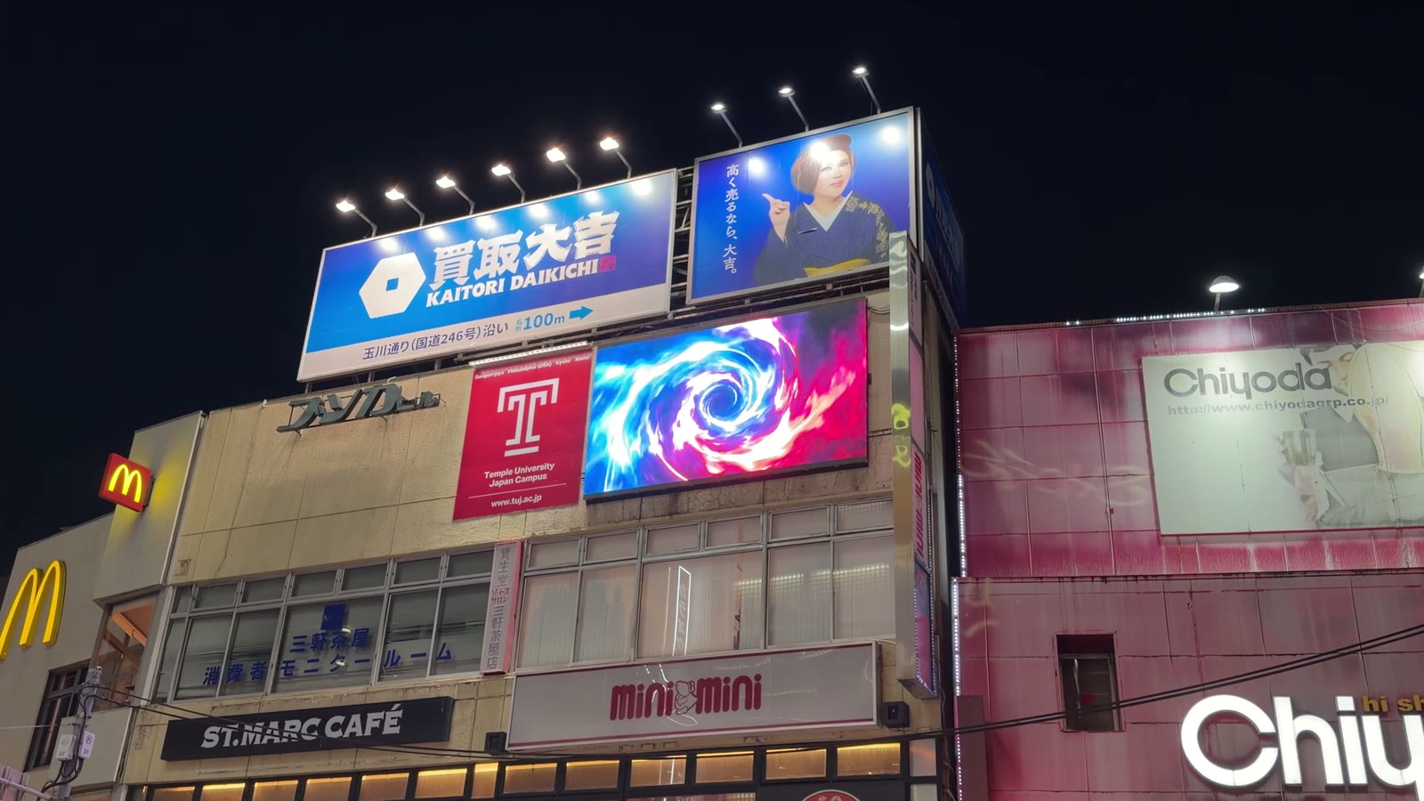 夜の三軒茶屋の駅前ビル屋上にある大型ビジョンに、抽象的な光の映像が流れている様子